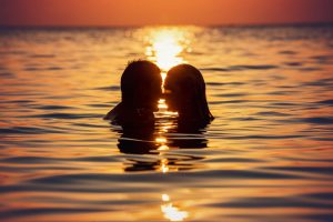 Posti dove fare l'amore: una coppia si bacia nell'acqua del mare al tramonto