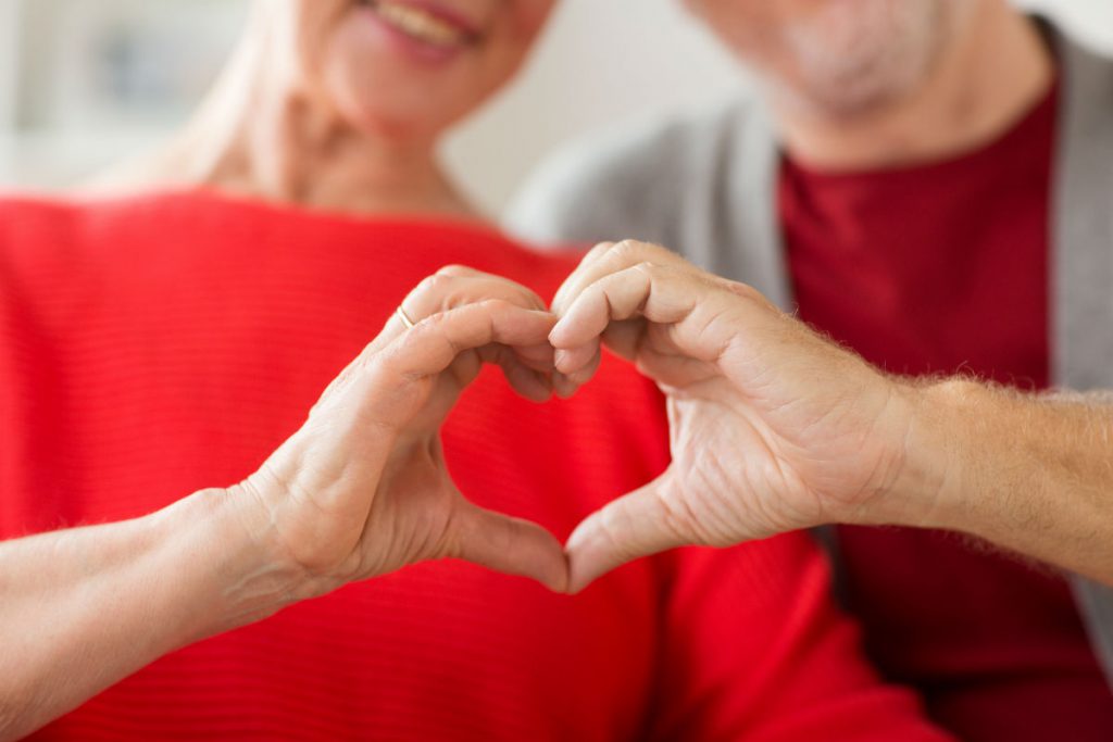 Sesso a 50 anni: nell'immagine una coppia over 50 compone un cuore unendo le dita delle mani