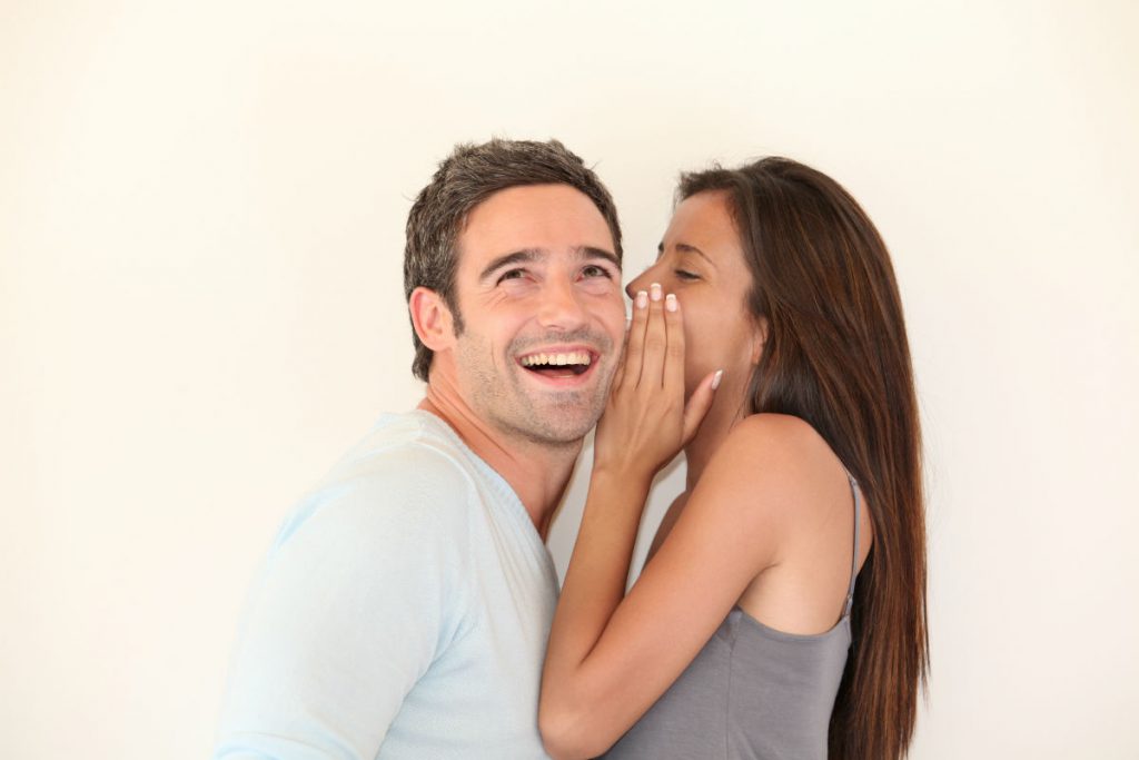 Una donna sussurra all'orecchio di un uomo le proprie fantasie sessuali